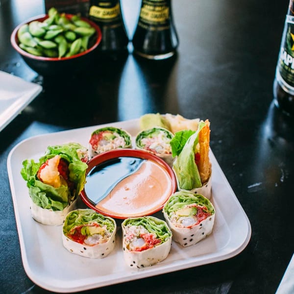 Sushi Omakase's fresh sushi rolls with lettuce, avocado, and shrimp, served with dipping sauces.